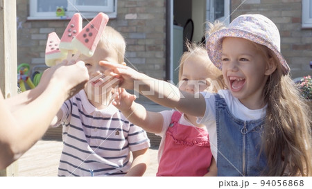 Three cute little Children enjoys delicious ice cream cone. Child eating watermelon popsicle. Kids Siblings snack sweets in Home Garden. Summer holiday Hot weather Sunny Day. Childhood, Food Candy Three cute little Children enjoys delicious ice cream cone. Child eating watermelon popsicle. Kids Siblings snack sweets in Home Garden. Summer holiday Hot weather Sunny Day. Childhood, Food Candy 94056868