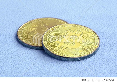 Two golden bitcoins lies on a blanket made of soft and fluffy light blue fleece fabric. Physical visualization of virtual crypto currency Two golden bitcoins lies on a blanket made of soft and fluffy light blue fleece fabric. Physical visualization of virtual crypto currency 94056978