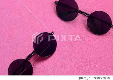 Two stylish black sunglasses with round glasses lies on a blanket made of soft and fluffy light pink fleece fabric. Fashionable background picture in female colors Two stylish black sunglasses with round glasses lies on a blanket made of soft and fluffy light pink fleece fabric. Fashionable background picture in female colors 94057010