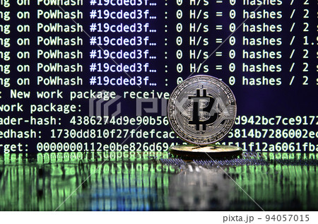 Two bitcoins lies on a videocard surface with background of screen display of cryptocurrency mining by using the GPUs 94057015