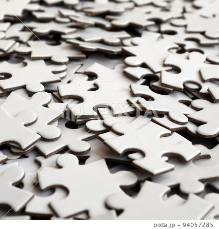 Close-up of a pile of uncompleted elements of a white puzzle. A huge number of rectangular pieces from one large white mosaic 94057285