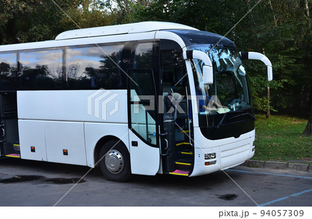 White tourist bus for excursions. The bus is parked in a parking lot near the park White tourist bus for excursions. The bus is parked in a parking lot near the park 94057309