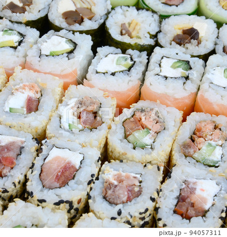 Close-up of a lot of sushi rolls with different fillings. Macro shot of cooked classic Japanese food. Background image 94057311