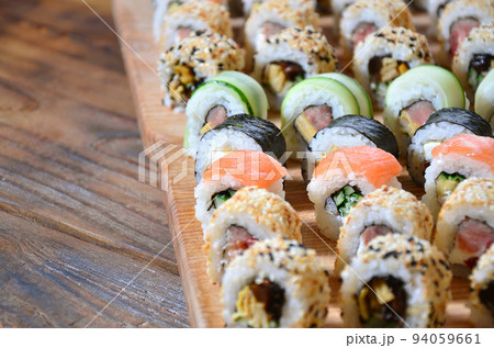 Sushi set of a number of rolls is located on a wooden cutting board on a table in the kitchen of a sushi bar. A traditional dish of oriental cuisine Sushi set of a number of rolls is located on a wooden cutting board on a table in the kitchen of a sushi bar. A traditional dish of oriental cuisine 94059661
