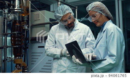 Two scientist in professional uniform working in laboratory Two scientist in professional uniform working in laboratory 94061765