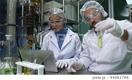 Two scientist in professional uniform working in laboratory Two scientist in professional uniform working in laboratory 94061766