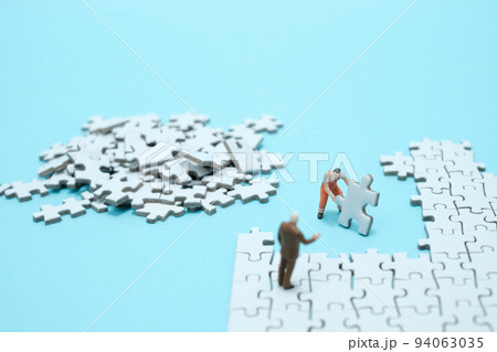 水色背景に白いパズルを組み立てる作業員と説教する会社員のフィギア 94063035