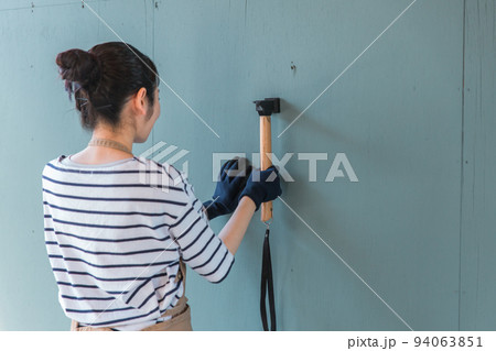 ガレージに釘を打つ日本人女性（リノベーション・DIY） 94063851