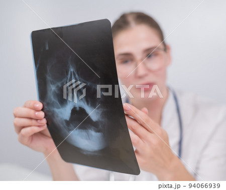 Female doctor looking at an x-ray of the sinuses. Female doctor looking at an x-ray of the sinuses. 94066939
