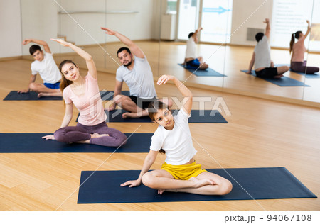 Family of four practicing yoga at gym 94067108