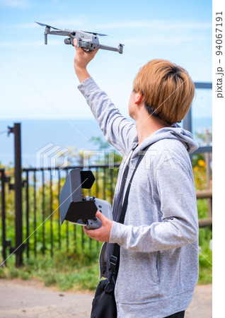 晴れた屋外でドローン撮影を楽しむ若い男性 94067191