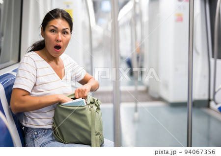 Oriental woman amazed by theft from her bag in subway car Oriental woman amazed by theft from her bag in subway car 94067356