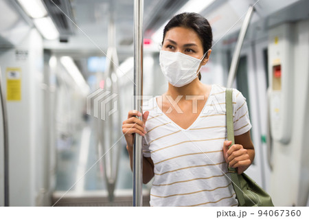 Woman in face mask standing in subway train Woman in face mask standing in subway train 94067360