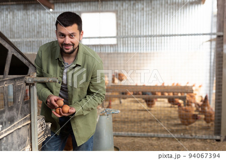 Man farmer collecting fresh eggs at henhouse 94067394