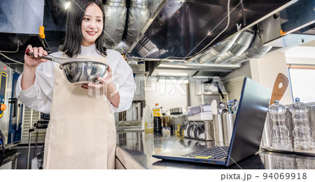 レストランの厨房で料理を学ぶ若い女性 94069918