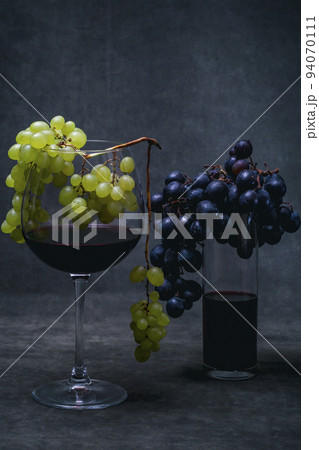 Glasses of red wine and bunches of grapes on a dark background 94070111