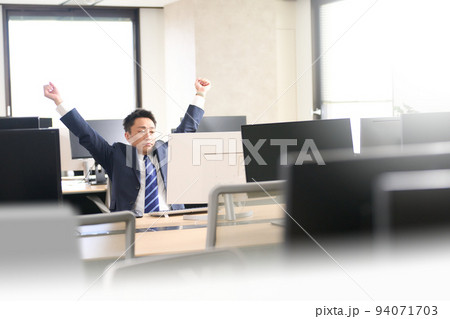 オフィスにて両手を広げて伸びをするビジネスマン 94071703
