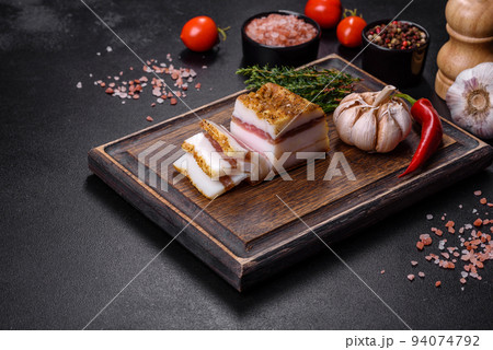 Smoked lard, bacon, half a piece, on a wooden dark cutting board Smoked lard, bacon, half a piece, on a wooden dark cutting board 94074792