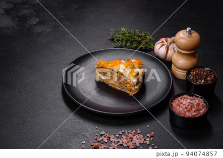 Delicious fresh liver cake with mayonnaise and carrots on a black plate against a dark concrete background 94074857