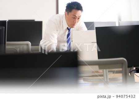 驚いた表情でPCのモニターを見つめるビジネスマン 94075432