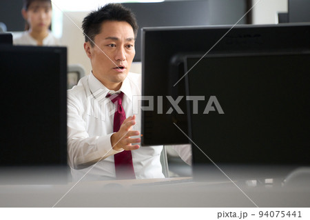 驚いた表情でPCのモニターを見つめるビジネスマン 驚いた表情でPCのモニターを見つめるビジネスマン 94075441