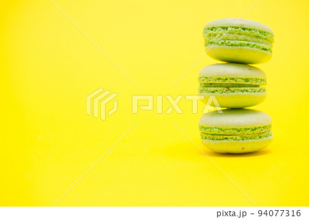 Delicious stack of green macaroons over yellow background. Luxury dessert 94077316