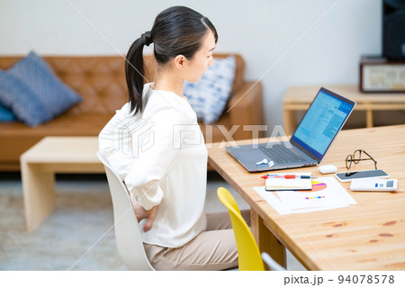 仕事中、腰痛に悩む女性 94078578