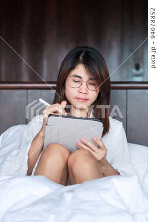 Happy woman using tablet for social media, young female watching movies on computer pad on bed at home. technology, network, online shopping, e commerce, lifestyle and digital communication concept Happy woman using tablet for social media, young female watching movies on computer pad on bed at home. technology, network, online shopping, e commerce, lifestyle and digital communication concept 94078852
