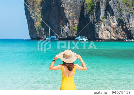 Woman tourist in yellow swimsuit and hat, happy traveller sunbathing at Maya Bay beach on Phi Phi island, Krabi, Thailand. landmark, destination Southeast Asia Travel, vacation and holiday concept 94079418