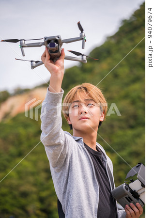 晴れた屋外でドローン撮影を楽しむ若い男性 94079674