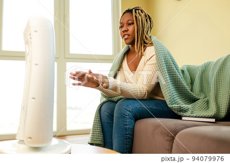 latin american woman with blanket in cold room with heater latin american woman with blanket in cold room with heater 94079976