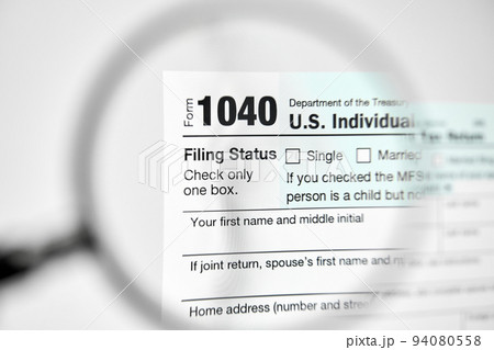 Looking through a magnifying glass at U.S. Individual Income Tax Return declaration form 1040 Looking through a magnifying glass at U.S. Individual Income Tax Return declaration form 1040 94080558