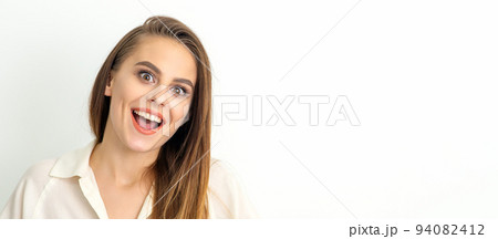 Portrait of a young caucasian happy woman wearing white shirt smiling with open mouth against the white background 94082412