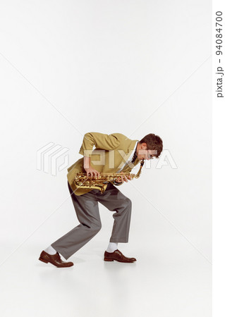 Portrait of young man in stylish yellow jacket playing saxophone isolated over white background. Jazz festival 94084700