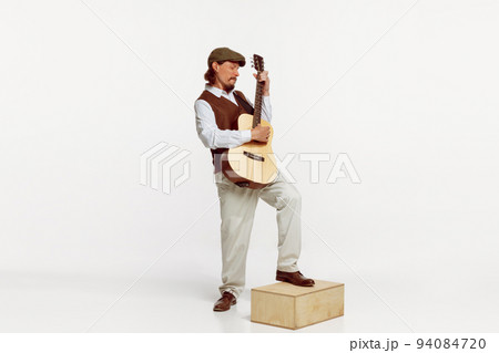 Portrait of stylish man playing guitar, performing isolated over white studio background. Keen singer Portrait of stylish man playing guitar, performing isolated over white studio background. Keen singer 94084720