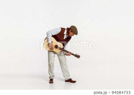 Portrait of stylish man playing guitar, performing isolated over white studio background. Live musician 94084733