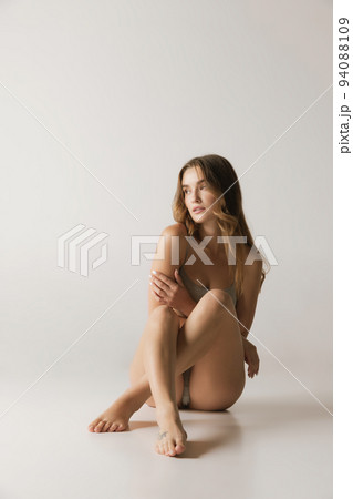 Studio shot of young charming slim girl in grey cotton underwear isolated over gray background. Wellness, fitness, diet, fashion, natural beauty of female body Studio shot of young charming slim girl in grey cotton underwear isolated over gray background. Wellness, fitness, diet, fashion, natural beauty of female body 94088109