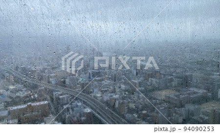 高層ビルの窓ガラスから見た雨の日の街並みの風景 94090253