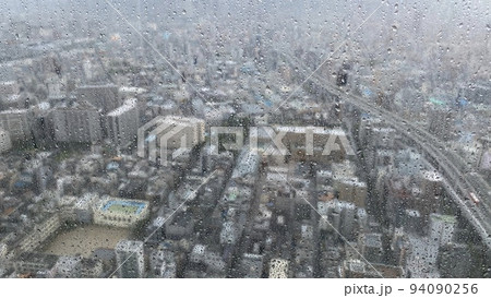 高層ビルの窓ガラスから見た雨の日の街並みの風景 94090256