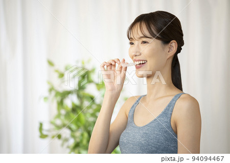 片手でマウスピースを持つ女性 94094467