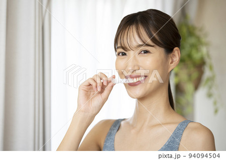 片手でマウスピースを持つ女性 94094504