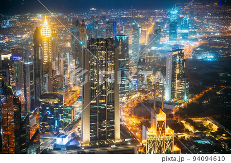Aerial view of urban cityscape skyline at night. City background of illuminated cityscape with skyscrapers and towers in Dubai. Street night traffic with illuminations. Urban background of Dubai, UAE 94094610