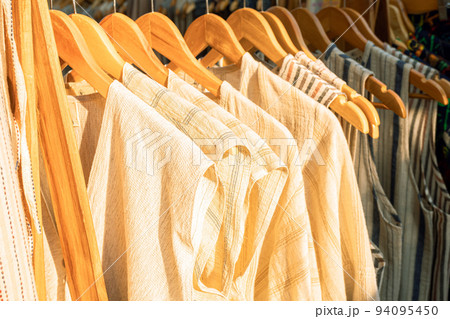 Bright colored clothes on wooden hangers on the market, Clothes shop in the outdoor market, Clothing trade. 94095450