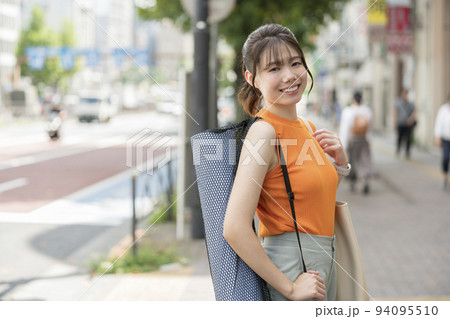 ヨガマットを持った若い女性 94095510