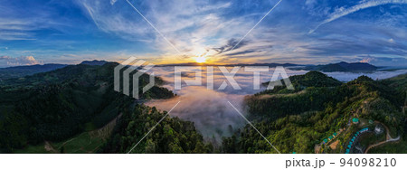 Aerial view Panorama of flowing fog waves on mountain tropical rainforest,Bird eye view image over the clouds Amazing nature background with clouds and mountain peaks in Thailand Aerial view Panorama of flowing fog waves on mountain tropical rainforest,Bird eye view image over the clouds Amazing nature background with clouds and mountain peaks in Thailand 94098210