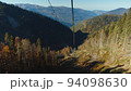 Scenic view from cable car cabin moving down among the autumn colored trees in magnificent caucasus mountains. downhill on cable road among forested mountain range. 94098630