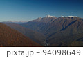 Gorgeous bird's eye view on the caucasus mountains in fall season. scenic lansscape of rosa khutor village drowning in forested mountain range with snowy peaks. 94098649