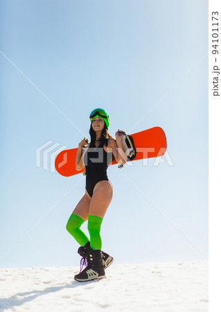 Young beautiful woman posing with a snowboard on a ski slope 94101173