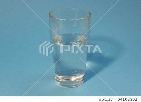 Half-filled glass of clean cold water on a light blue background. Healthy life, proper nutrition, drink plenty of water. 94102802