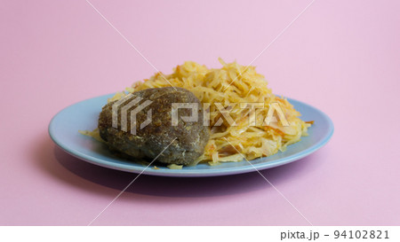 Stewed white cabbage with a cutlet steak on a plate. A dish of Russian, Polish cuisine. Garnish in the USSR. Stewed white cabbage with a cutlet steak on a plate. A dish of Russian, Polish cuisine. Garnish in the USSR. 94102821